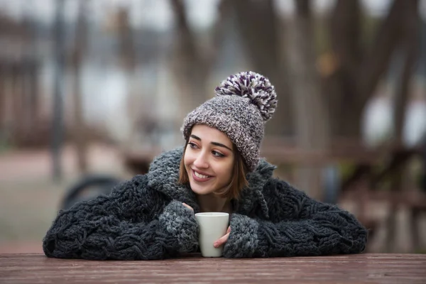 Happy and Smiling White Girl Drinking Coffee on the Street with a Coat