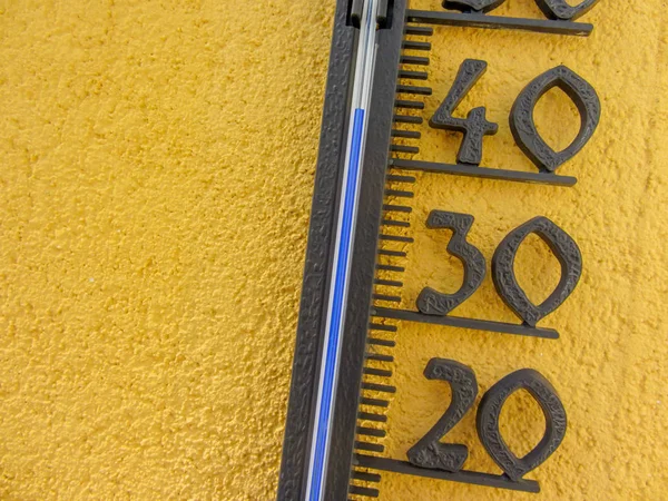 Termômetro na parede amarela medindo a temperatura do ar externo ao longo de quarenta graus celsius — Fotografia de Stock