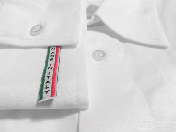 Vyrobeno v Itálii štítku na bílou košili — Stock fotografie