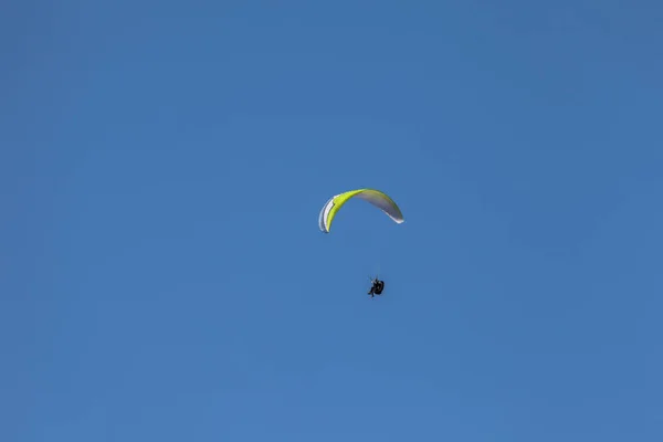 Человек, прыгающий на параплане в голубом небе над Доломитами в Италии в солнечный день — стоковое фото