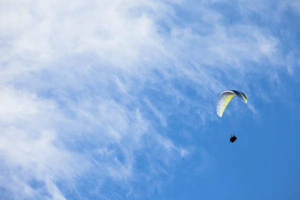 Человек, прыгающий на параплане в голубом небе над Доломитами в Италии в солнечный день — стоковое фото