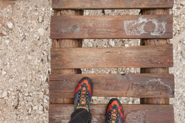 Küçük tahta bir köprü boyunca yürüyen bir yürüyüşçü.