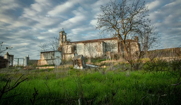 Övergiven kyrka ruin och kyrkogård igenväxta landskap — Stockfoto