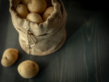 Yumuşak pencerelerde sade ahşap arka planda, çuval bezli patatesler hafif gıda mahsulü.