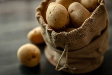 Yumuşak pencerelerde sade ahşap arka planda, çuval bezli patatesler hafif gıda mahsulü.