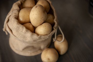 Yumuşak pencerelerde sade ahşap arka planda, çuval bezli patatesler hafif gıda mahsulü.
