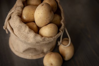 Yumuşak pencerelerde sade ahşap arka planda, çuval bezli patatesler hafif gıda mahsulü.