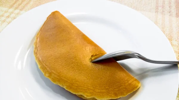 Der Pfannkuchen mit Löffel auf weißem Teller und Baumwollhintergrund — Stockfoto