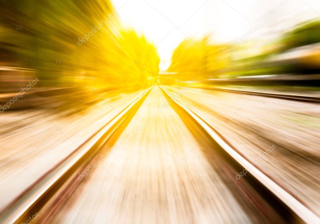 the motion blur of railway moving forward by train among warm sunshine