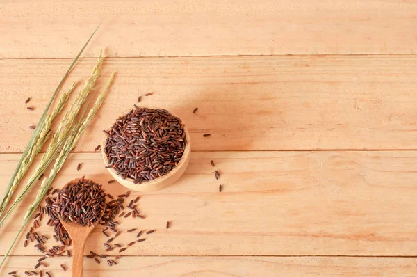 木製のテーブル背景に乾燥した稲をボウルで生玄米. — ストック写真
