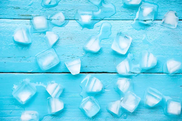 冷たい氷が青い木製の背景の部分溶融です。 — ストック写真