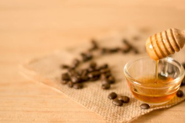 Bal ayı ve güzel kokulu bal ile kahve çekirdeği ahşap zemin üzerine saydam bir kase içine. Seçici ve yumuşak odak Bowl