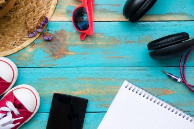 pembe güneş gözlüğü ile kırmızı spor ayakkabı, örme şapka, cep telefonu, dizüstü bilgisayar ve kulaklık eski mavi ahşap zemin arka plan. grafik tasarımcı için kopyalama alanı