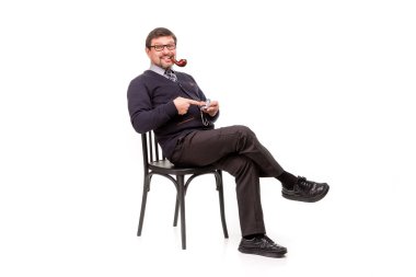 Bir takım elbise ve gözlük, yakışıklı bir adam oturuyor, smok bir boru ile