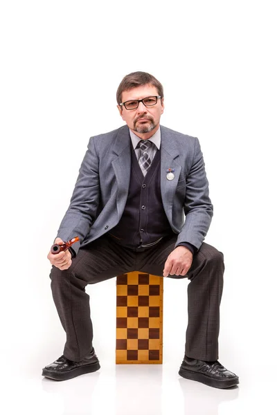 En stilig man i kostym och glasögon, med schack och en pipe för — Stockfoto