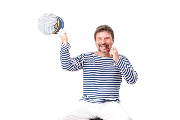 A man sailor in a cap with a smoking pipe in front of a white ba — Stock Photo, Image