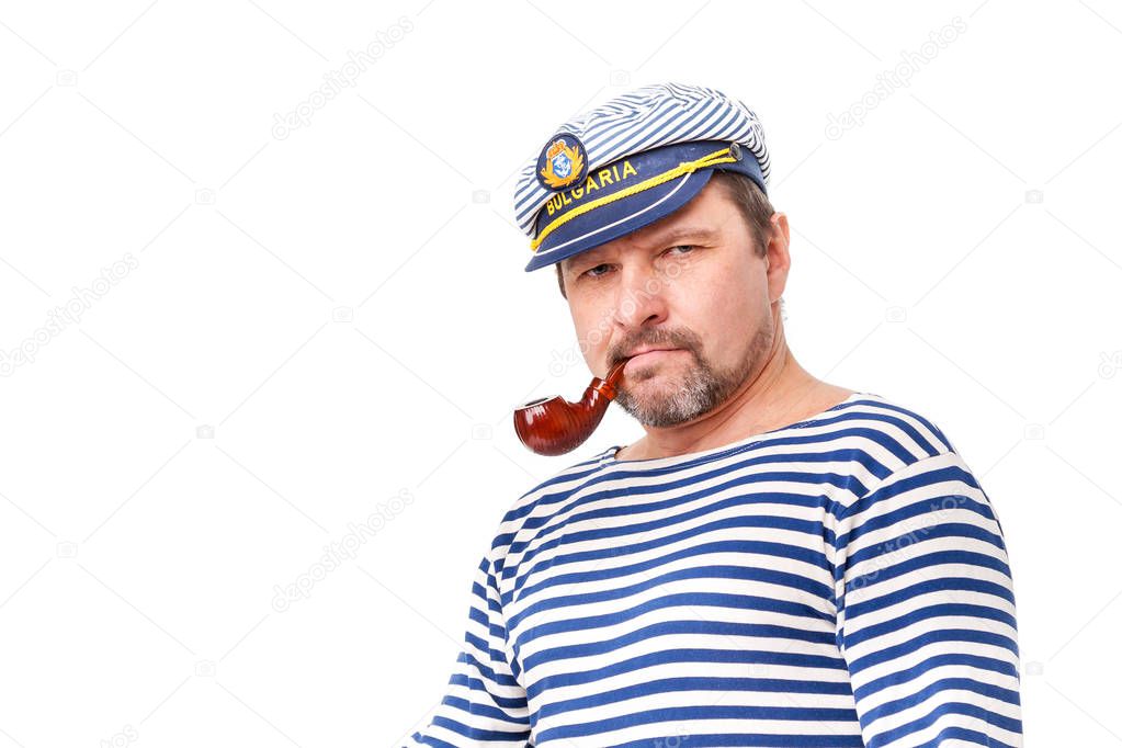 A man sailor in a cap with a smoking pipe in front of a white ba
