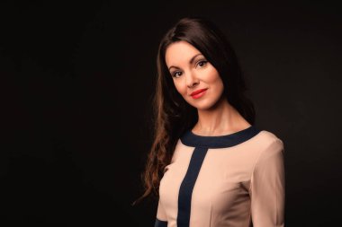 Karanlık bir arka plan üzerinde bej elbiseli güzel kız