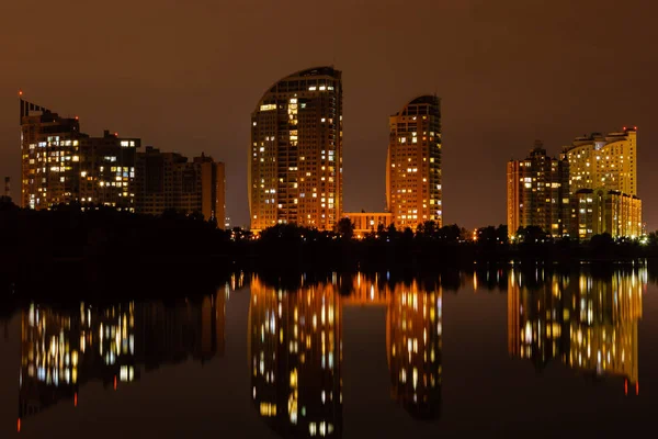 Night city with reflection of houses in the river — Stock Photo, Image