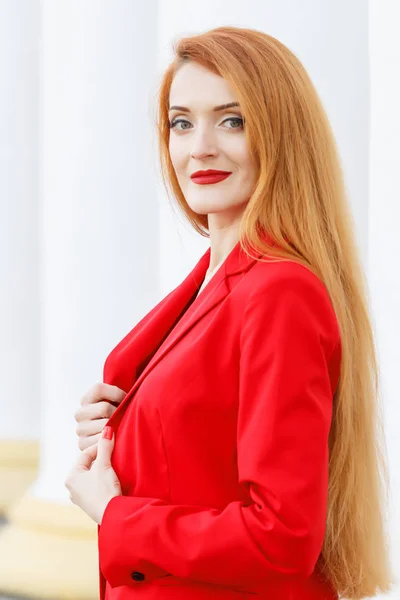 Schöne Mädchen mit roten Haaren in einem roten Business-Anzug gekleidet. Bus — Stockfoto