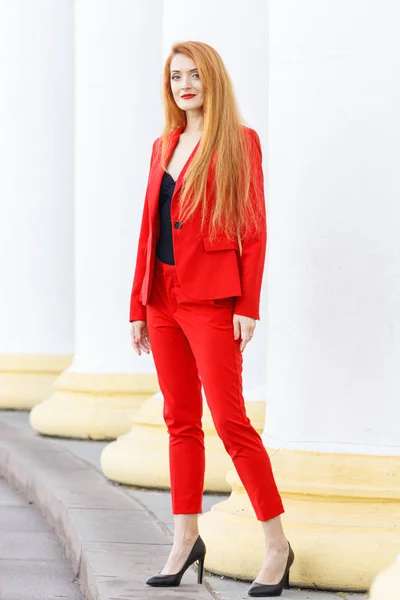 beautiful girl with red hair dressed in a red business suit. Bus
