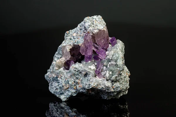 Macro mineral amethyst stone in rock on a black background — ストック写真