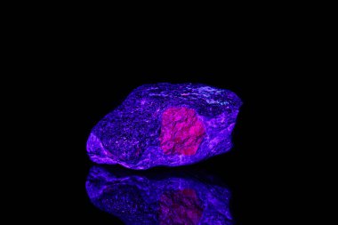 macro mineral stone ruby under ultraviolet light on a black back clipart
