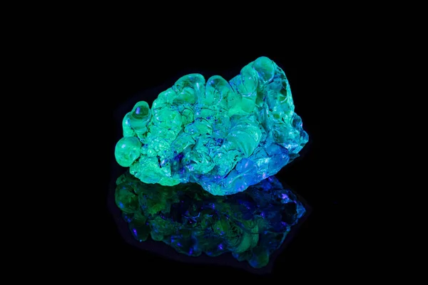 Opale di pietra minerale macro sotto luce ultravioletta su un dorso nero — Foto Stock