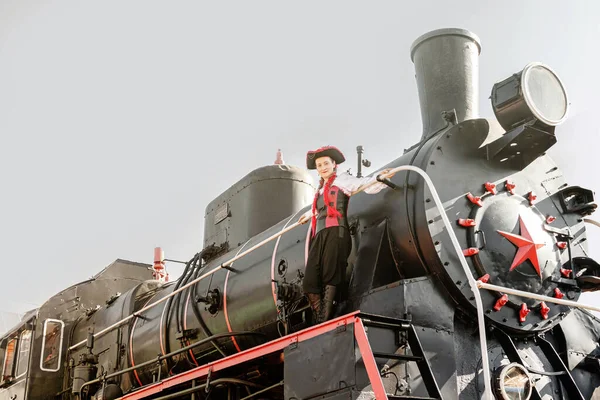 beautiful girl in a steampunk suit on a background of an old train close-up