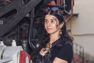 Steampunk elbiseli güzel bir kız trenin arka planında. Yaklaş.