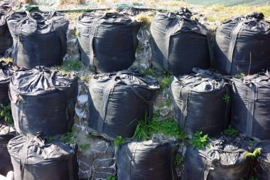 Nehir kıyısına yığılmış felaket önleme kum torbaları