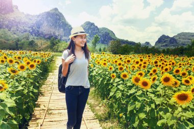 Sırt çantası ve hasır şapka ayçiçeği arayan kadın ile seyahat
