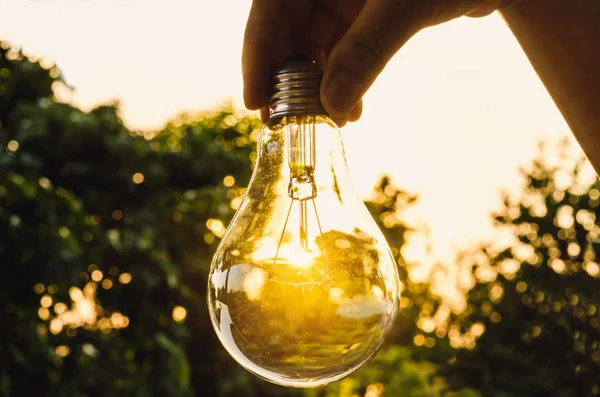 Hand hält eine Glühbirne mit Sonnenuntergang Power-Konzept macht die fu — Stockfoto