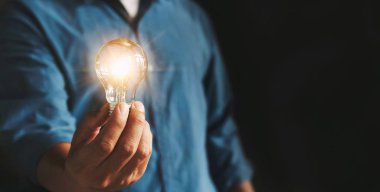 businessman hand holding lightbulb. idea Alternative energy conc clipart