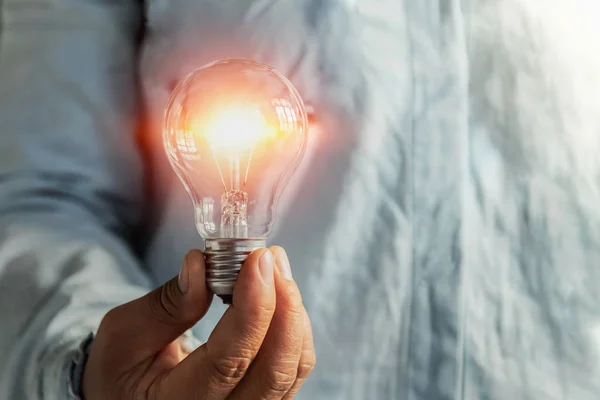 Geschäftsmann hält Glühbirne in der Hand. Idee alternative Energien — Stockfoto