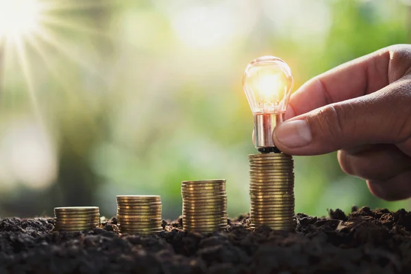 Business man hand holding lightbulb money stack. idea saving ene — Stock Photo, Image