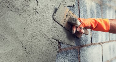 İnşaat için duvara beton yapıştıran el işçilerini kapatın.