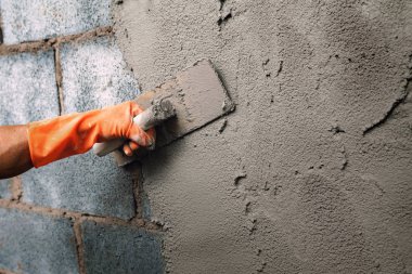 Ev inşaatı için duvara çimento yapıştıran yakın çekim el işçisi.