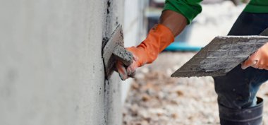 Ev inşaatı için duvara çimento yapıştıran yakın çekim el işçisi.