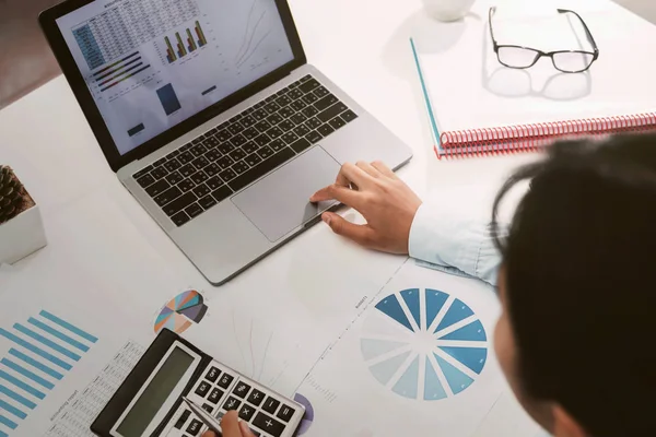 businesswoman working on desk using calculator and laptop analyz