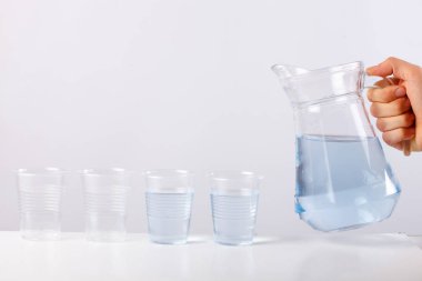 Beyaz arka plan cam için cam sürahi su dökerek el