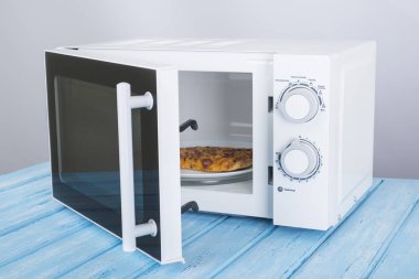 Yeni beyaz mikrodalga fırın, mavi ahşap yüzeye Isıtma için