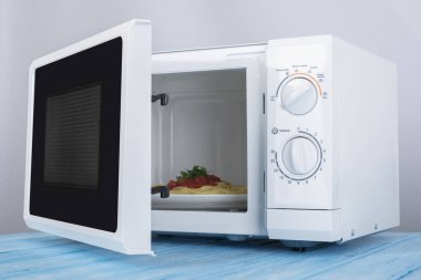 Yeni beyaz mikrodalga fırın, mavi ahşap yüzeye Isıtma için