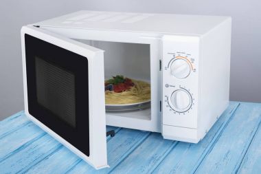 Yeni beyaz mikrodalga fırın, mavi ahşap yüzeye Isıtma için