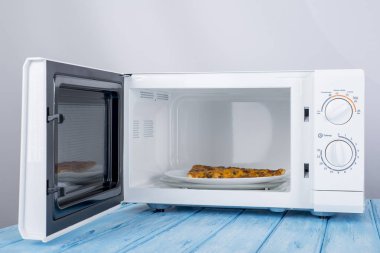 Yeni beyaz mikrodalga fırın, mavi ahşap yüzeye Isıtma için