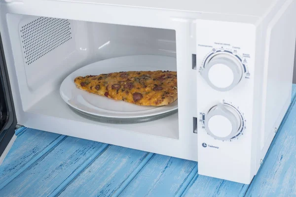A new white microwave oven, on a blue wooden surface for heating