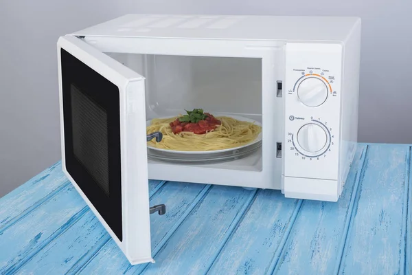 A new white microwave oven, on a blue wooden surface for heating — Stock Photo, Image