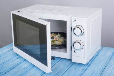 Gıda Isıtma için mavi bir ahşap yüzey üzerinde beyaz mikrodalga fırın