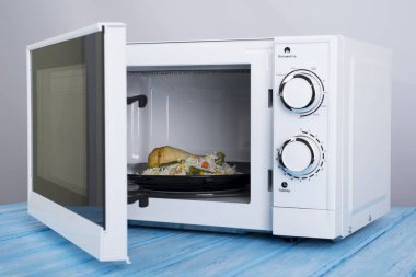 Gıda Isıtma için mavi bir ahşap yüzey üzerinde beyaz mikrodalga fırın