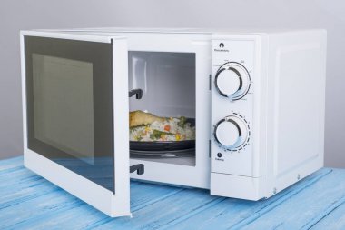 Gıda Isıtma için mavi bir ahşap yüzey üzerinde beyaz mikrodalga fırın